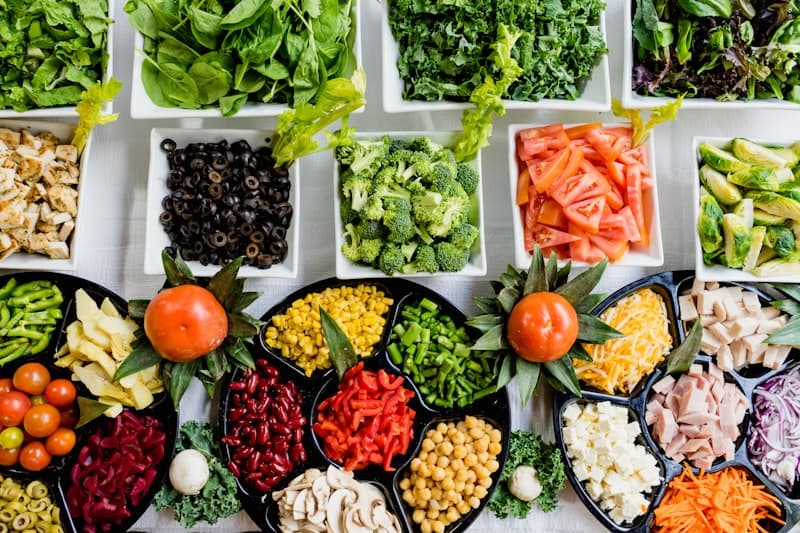 Wide variety of anti-inflammatory foods — blueberries, salmon fillet, broccoli, walnuts, turmeric, and green tea spread on a table