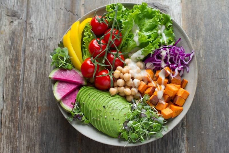 Colorful spread of anti-inflammatory foods including turmeric, berries, salmon, leafy greens, and olive oil arranged on a wooden table