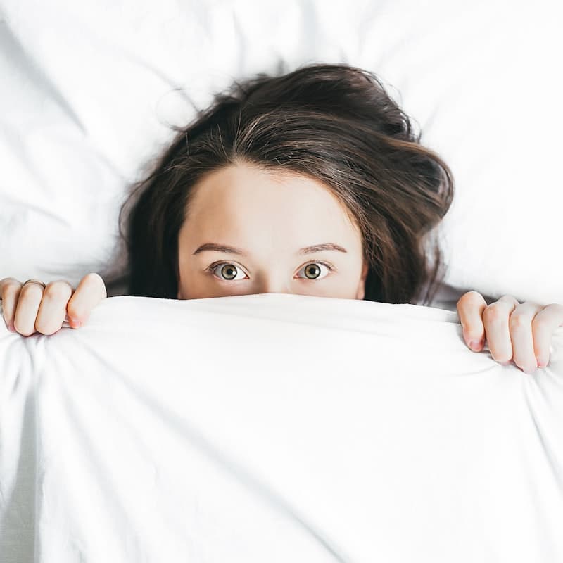 Person lying awake at night rubbing their restless legs — a magnesium glycinate supplement on the nightstand